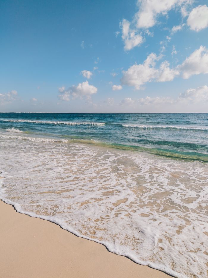 Relaxing ocean waves lapping a sandy beach under a clear blue sky.